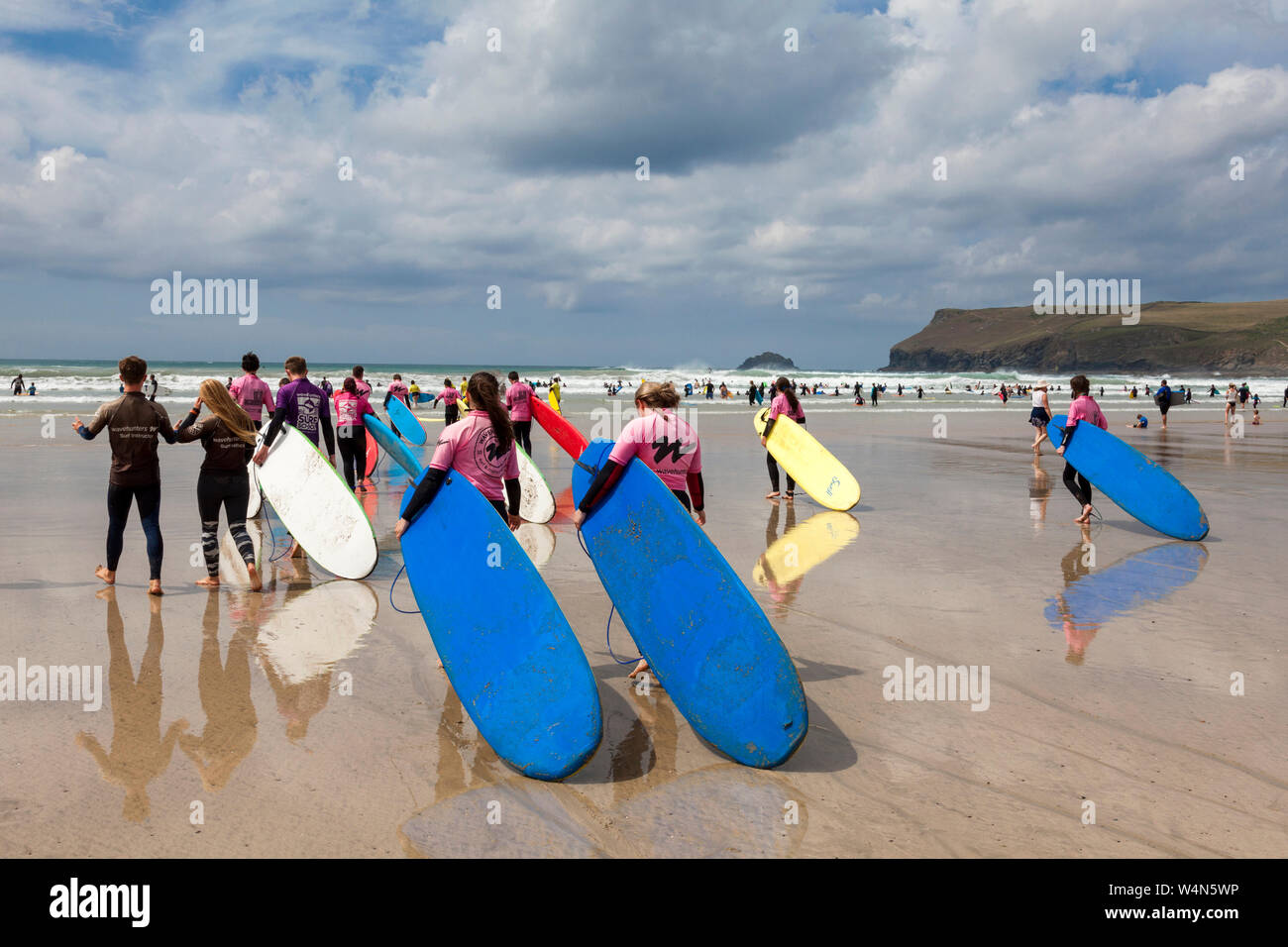 Polzeath, Cornwall, Regno Unito. Il 24 luglio 2019. Testa di surfisti le onde in un caldo e assolato pomeriggio su Polzeath Beach sulla North Cornwall dalla costa atlantica. Foto Stock