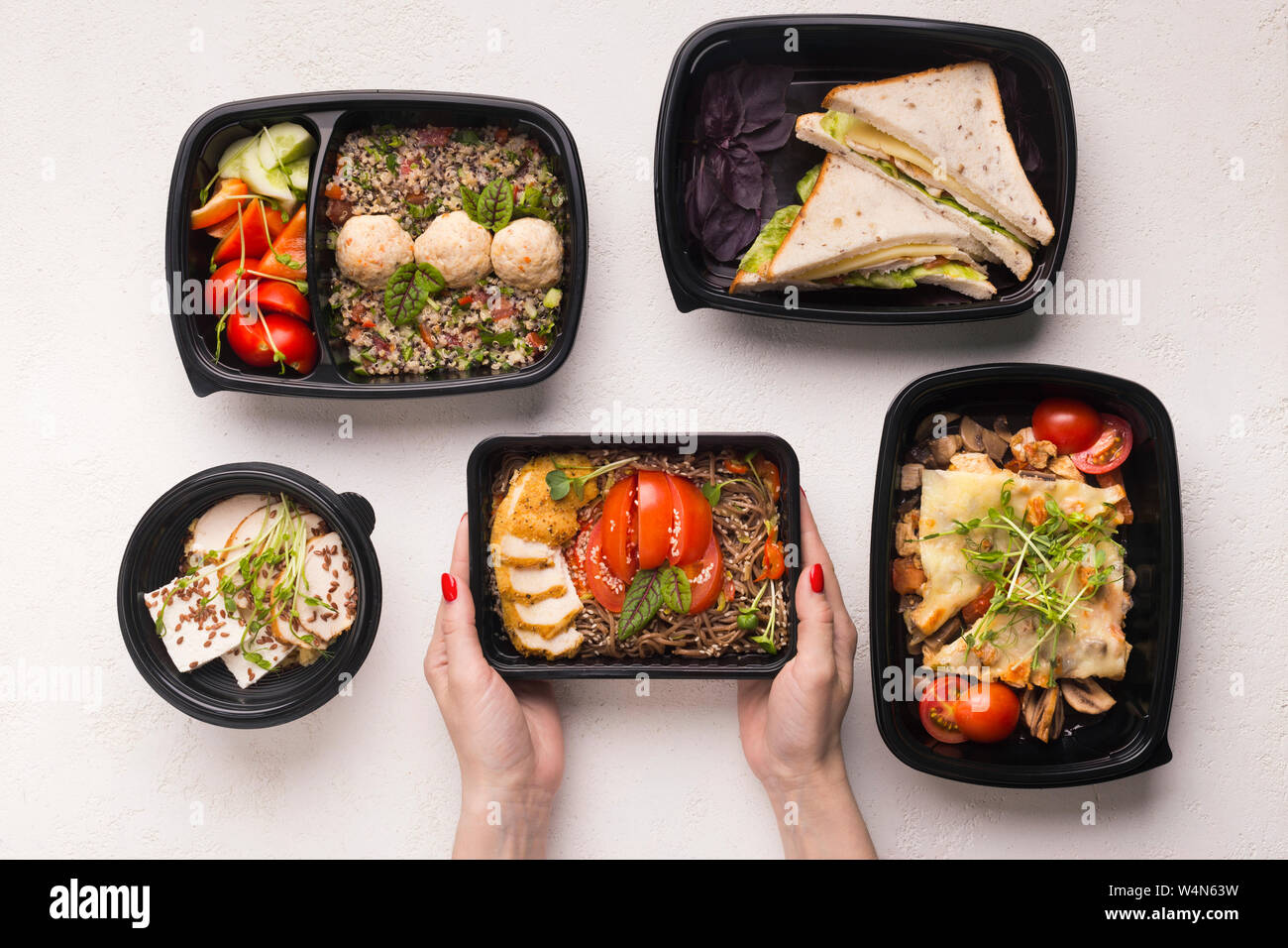 Il cibo gustoso in diverse caselle per razione di giorno in mani donna Foto Stock