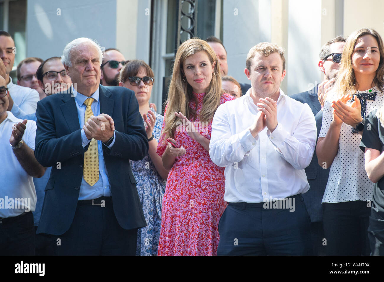 Il nuovo Primo Ministro Boris Johnson il partner Carrie Symonds ascolta come egli fa un discorso al di fuori 10 Downing Street, Londra, dopo un incontro con la regina Elisabetta II e di accettare il suo invito a diventare Primo Ministro e formare un nuovo governo. Foto Stock