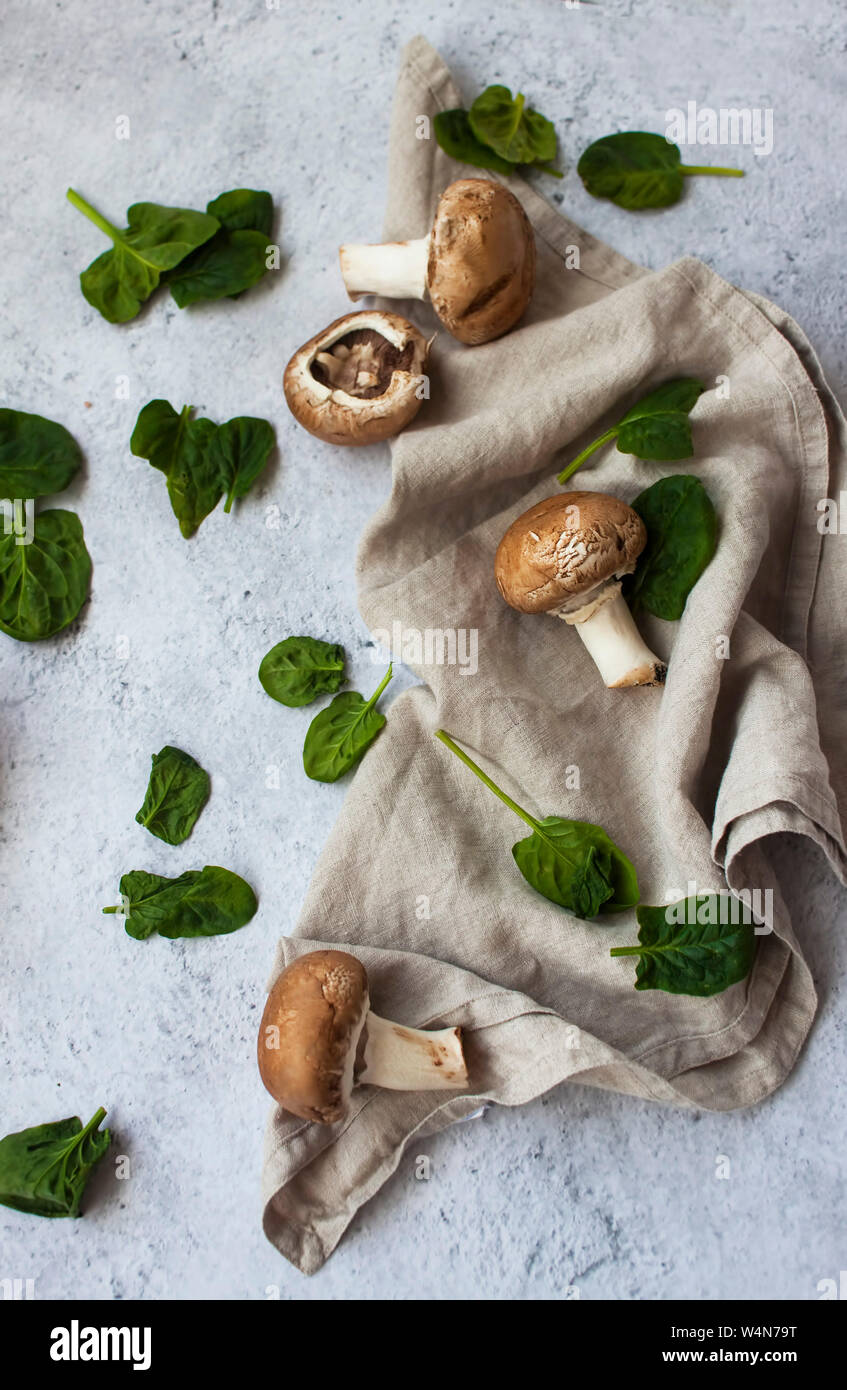 Fresh baby spinaci e champignon marrone su crem igienico su sfondo grigio. Foto Stock