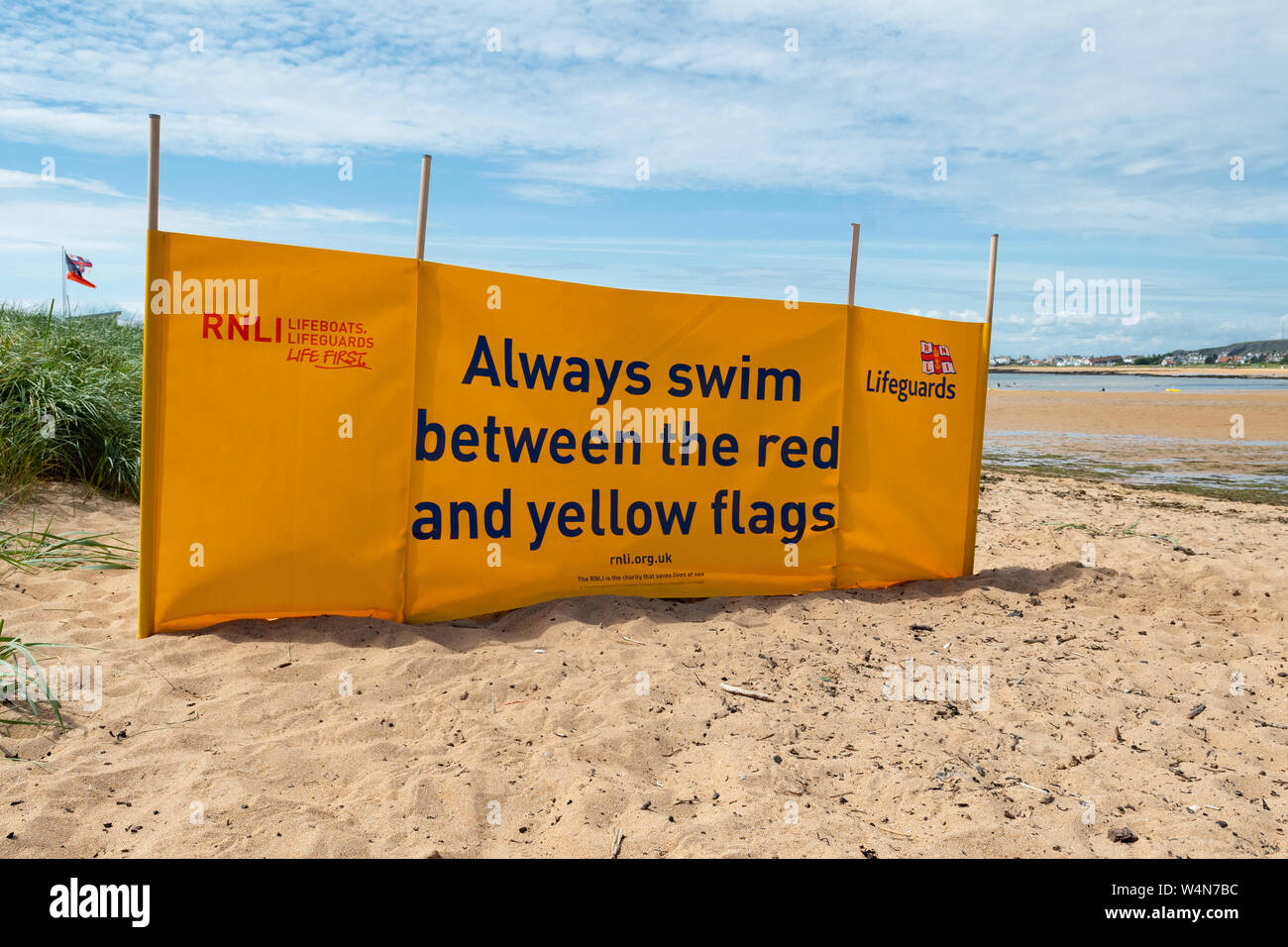 Sempre nuotare tra il giallo e il rosso bandiere banner a Elie beach, Fife, Scozia, Regno Unito Foto Stock