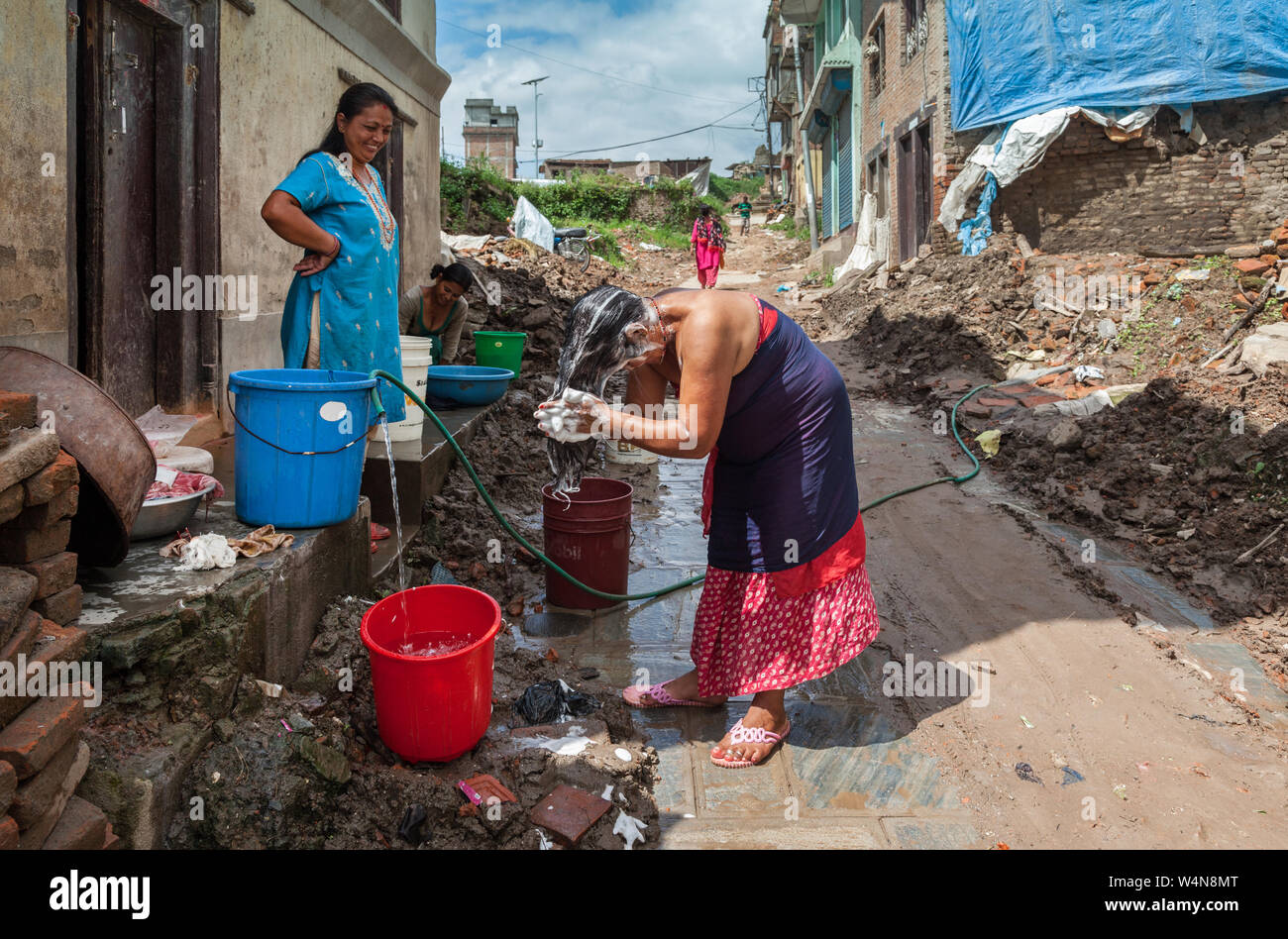 Le donne lavare i capelli su una strada danneggiata da un terremoto nel Nepal Foto Stock