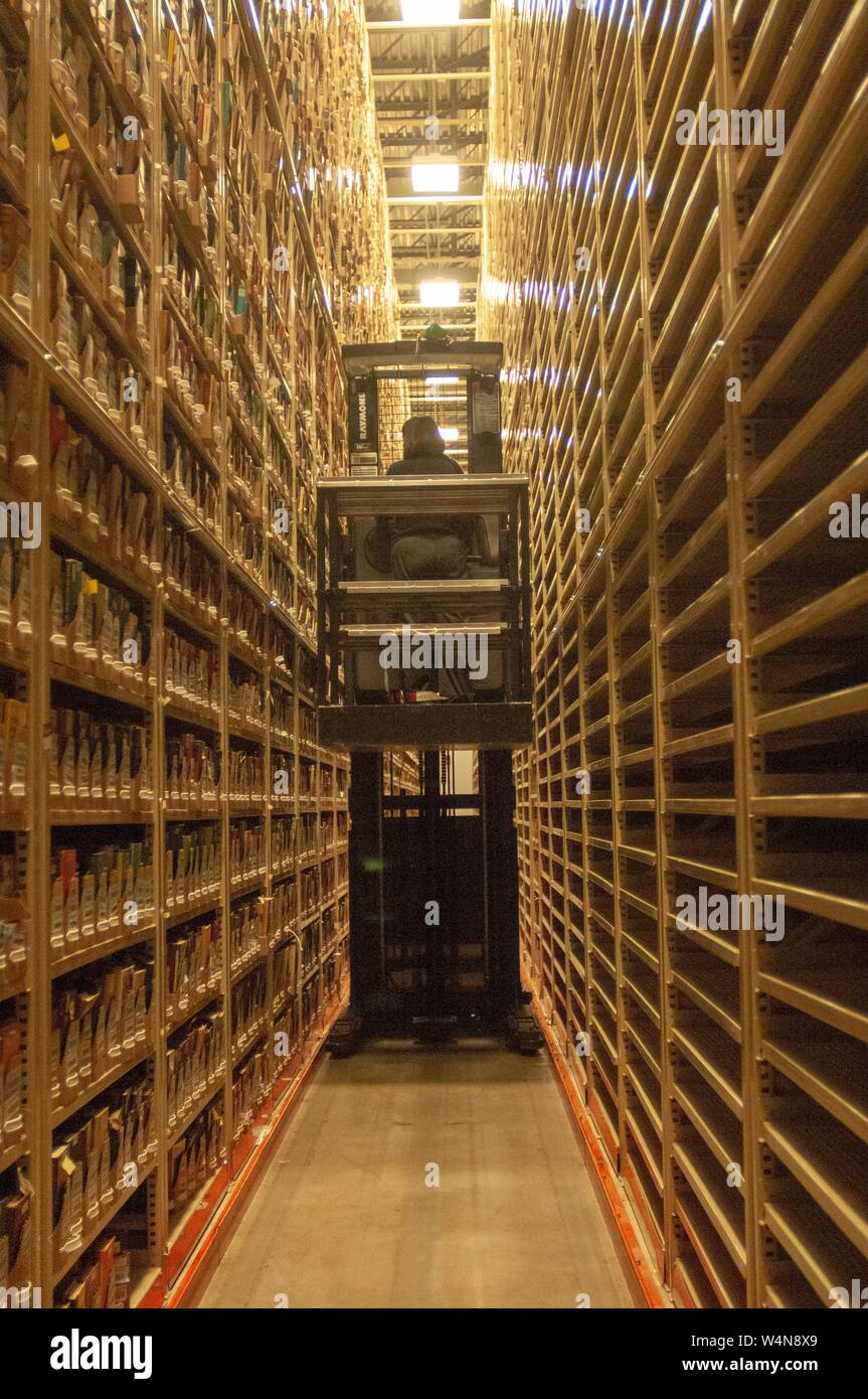 Una persona, dal retro, aziona un sollevamento motorizzato attraverso alte pile di supporti, in un impianto di stoccaggio di Milton S Eisenhower biblioteca presso la Johns Hopkins University, Baltimora, Maryland, 13 febbraio 2006. Dall'Homewood raccolta di fotografie. () Foto Stock