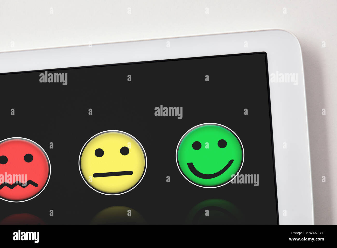 Soddisfazione dei livelli di rappresentazione con le emoticon con nero schermo tablet sul tavolo bianco vicino. Composizione orizzontale. Vista dall'alto. Foto Stock