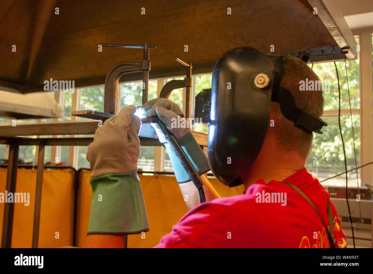 Profilo di close-up di una saldatrice, che indossa un casco di protezione e guanti, lavora in un negozio di macchina presso la Johns Hopkins University, Baltimora, Maryland, Ottobre 2, 2006. Dall'Homewood raccolta di fotografie. () Foto Stock