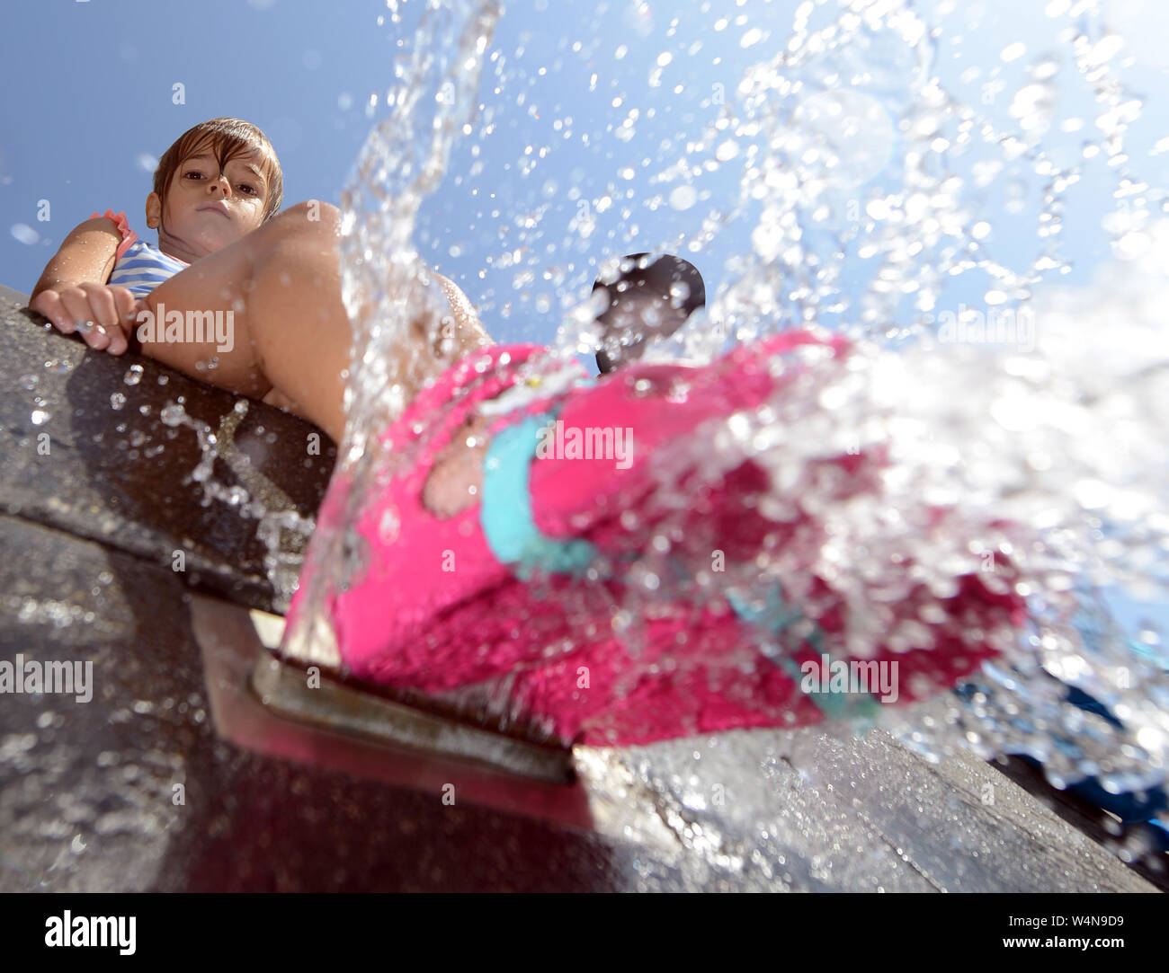 24 luglio 2019, Renania-Palatinato, Völklingen: Mathilda raffredda i suoi piedi su una parete con gorgogliamento di acqua fuori di esso. Oggi Völklingen è uno dei punti più caldi in Germania. Foto: Harald Tittel/dpa Foto Stock
