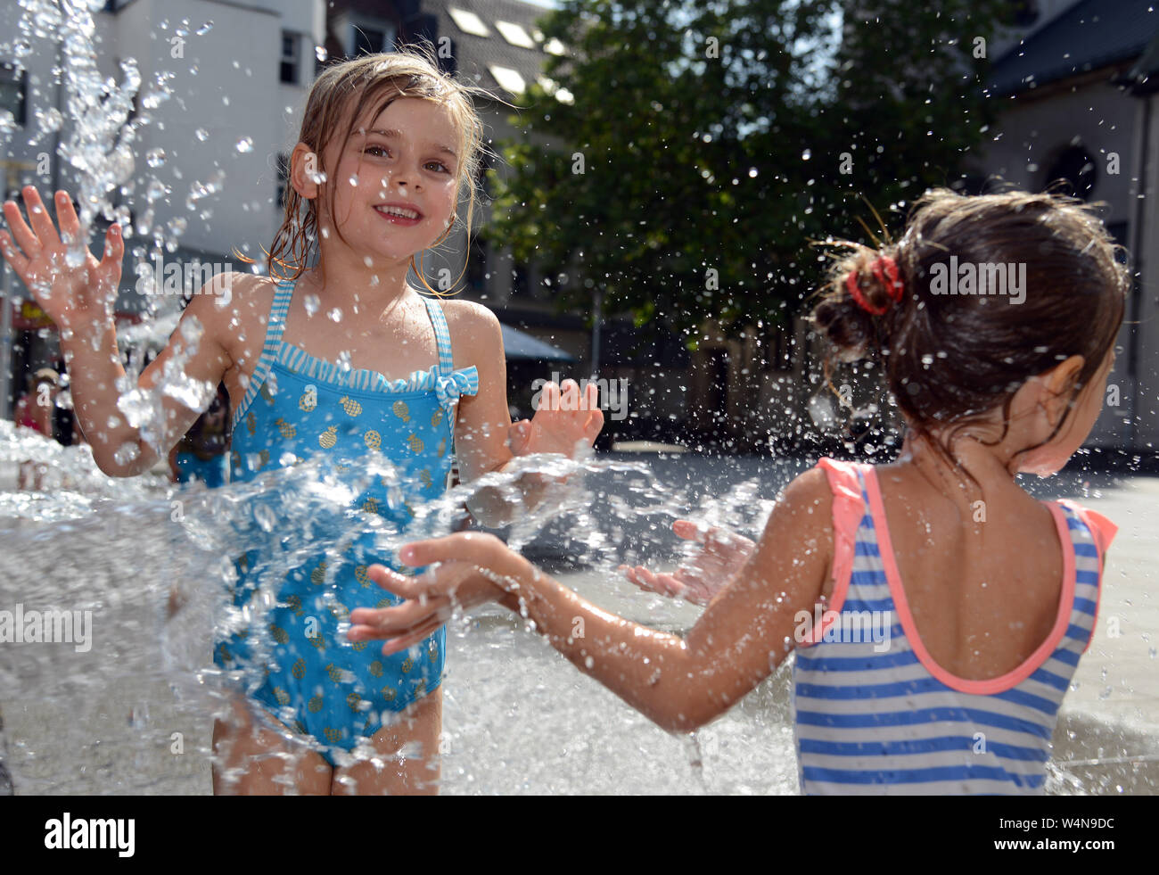 24 luglio 2019, Renania-Palatinato, Völklingen: Nele (l) e Mathilda rinfrescarsi in una fontana di acqua il gorgogliamento di una parete nella zona pedonale. Oggi Völklingen è uno dei punti più caldi in Germania. Foto: Harald Tittel/dpa Foto Stock
