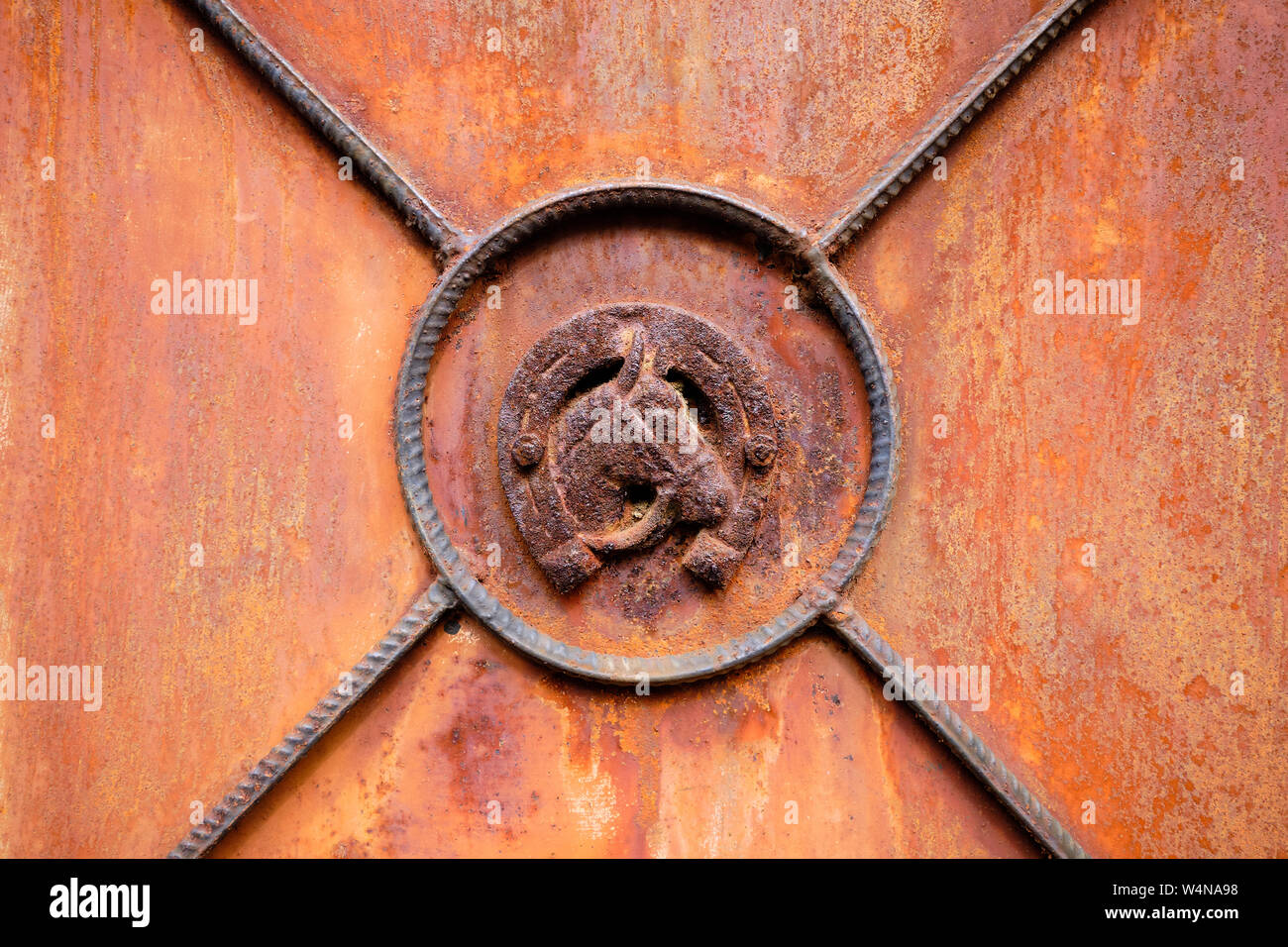 Testa di cavallo è incorniciato a ferro di cavallo sulla chiusura del vecchio arrugginito abbandonato la porta di metallo Foto Stock