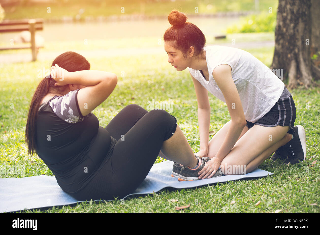 Personal trainer coach teen aiutare la formazione di grassi amico ragazza di esercitare la dieta per un sano all'aperto nel parco Foto Stock