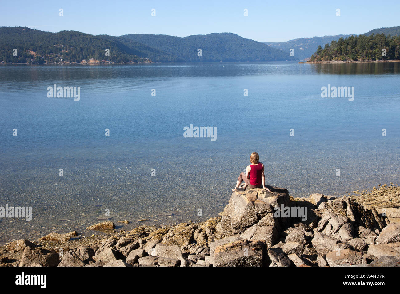 Donna seduta pacificamente su roccia, Todd ingresso, British Columbia, Canada Foto Stock