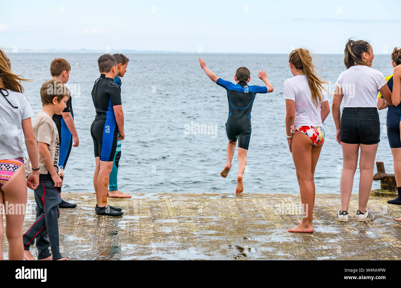 A North Berwick, East Lothian, Scozia, Regno Unito, 24 luglio 2019. Regno Unito Meteo: ragazzi e ragazze locali trattare con la canicola estiva che salta fuori il vecchio molo nel Firth of Forth per raffreddarsi Foto Stock