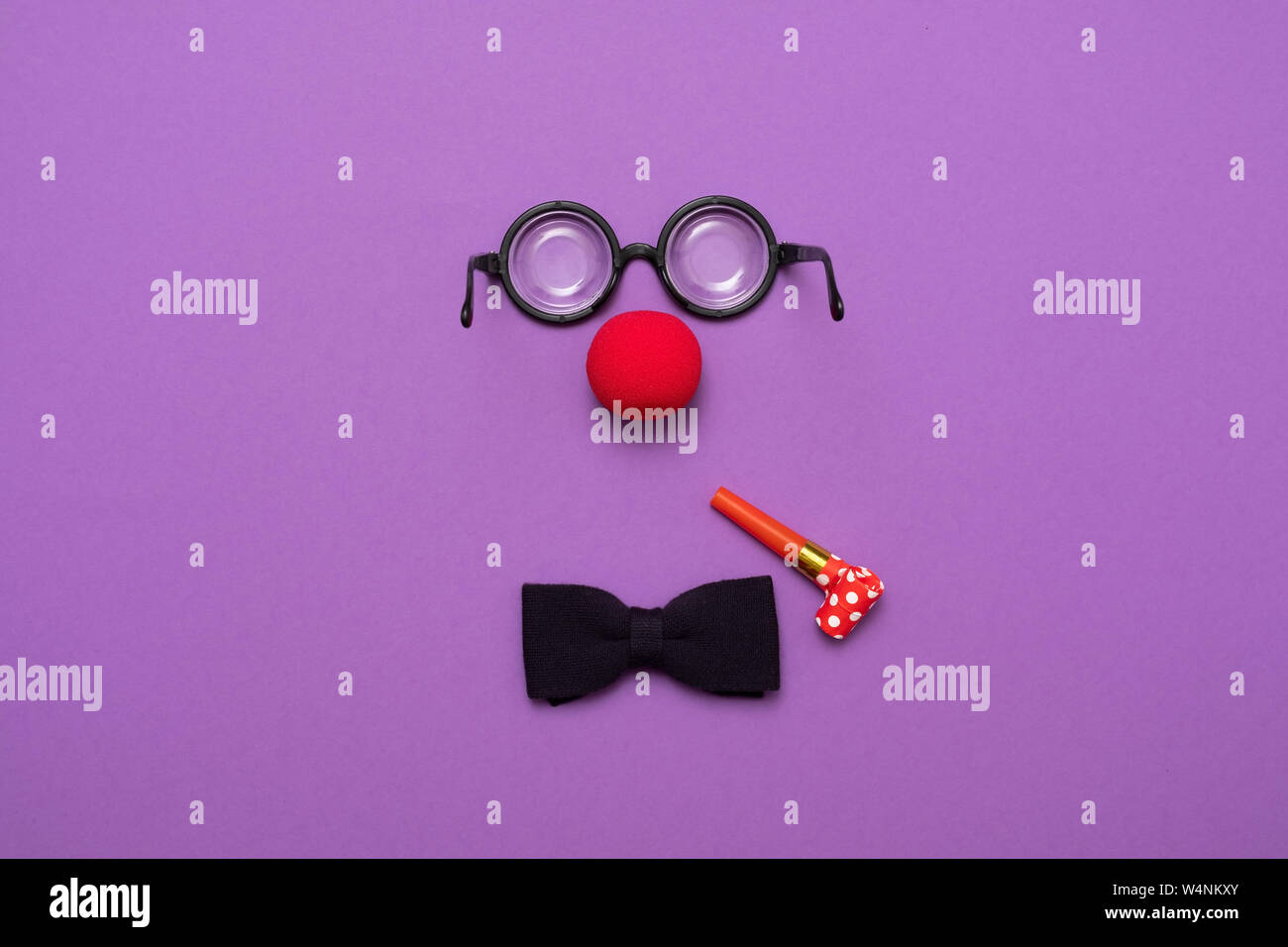 Occhiali buffi, rosso clown naso e tirante giacciono su uno sfondo colorato, come una faccia. Foto Stock