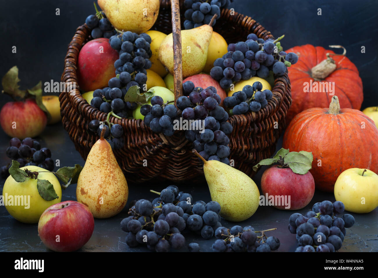 Autunno still life con mele, uva, la zucca e le pere situato su uno sfondo scuro, raccolto autunnale, mele, pere e uva nel cestello, orizzontale Foto Stock
