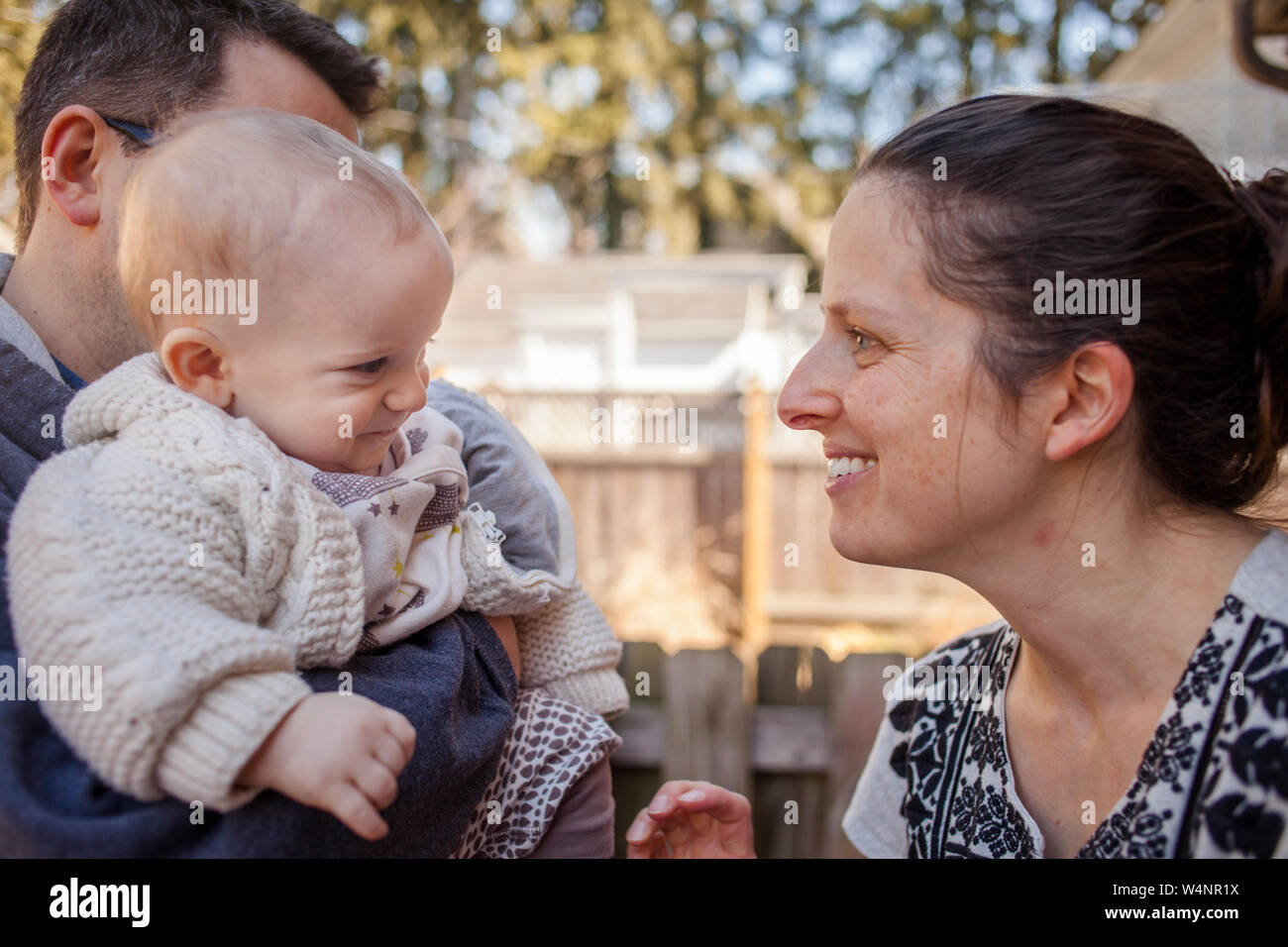 Un happy baby sorrisi a madre mentre viene mantenuto in padre di braccia Foto Stock