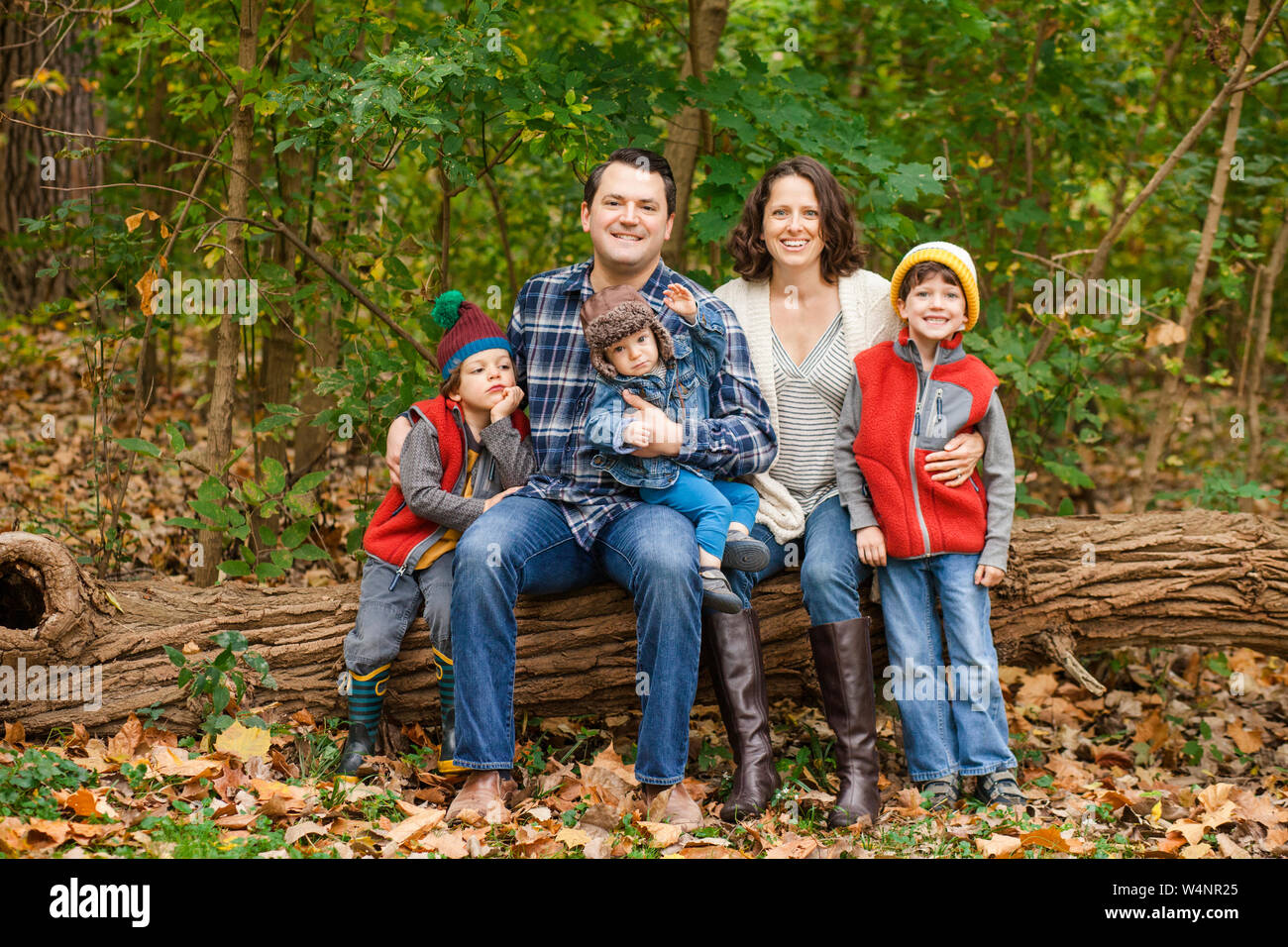 Una famiglia sorridente sedersi insieme su un registro nel bosco Foto Stock