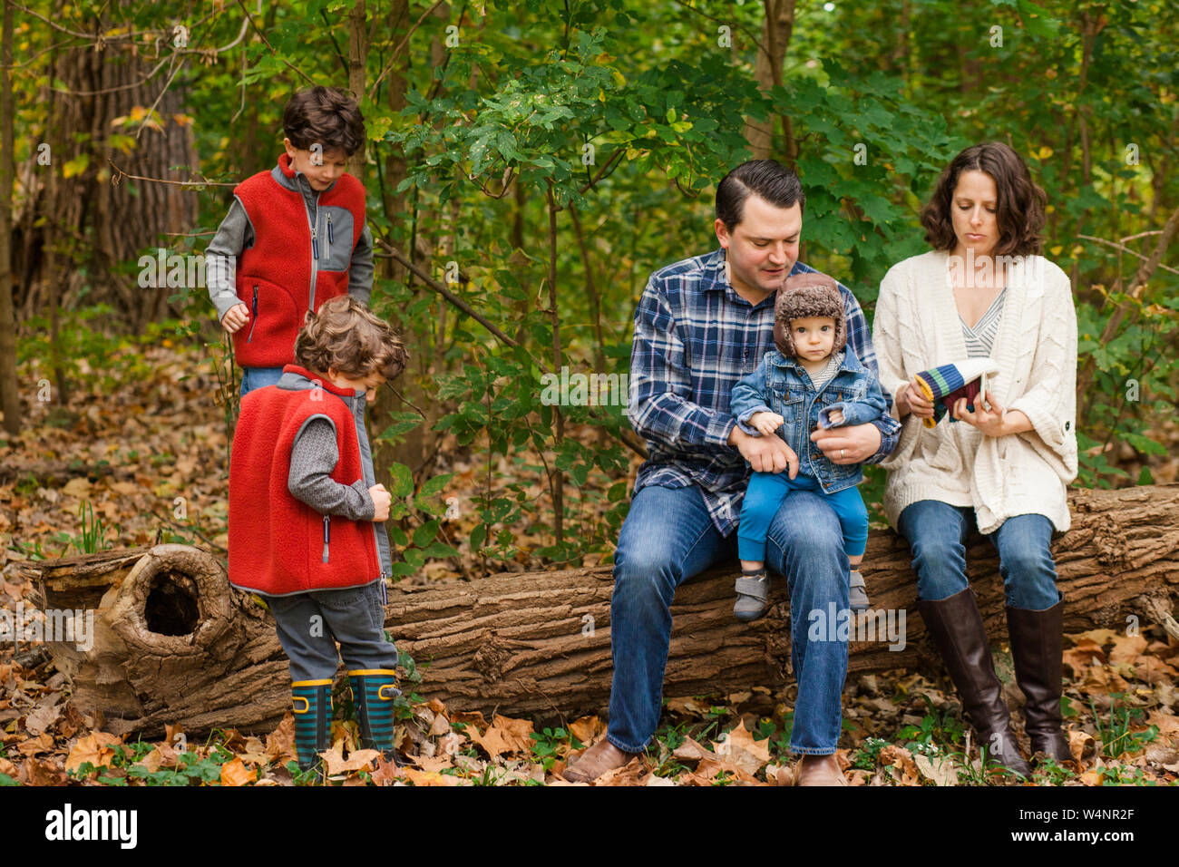 Una famiglia giocare insieme su un log in un parco boscoso Foto Stock