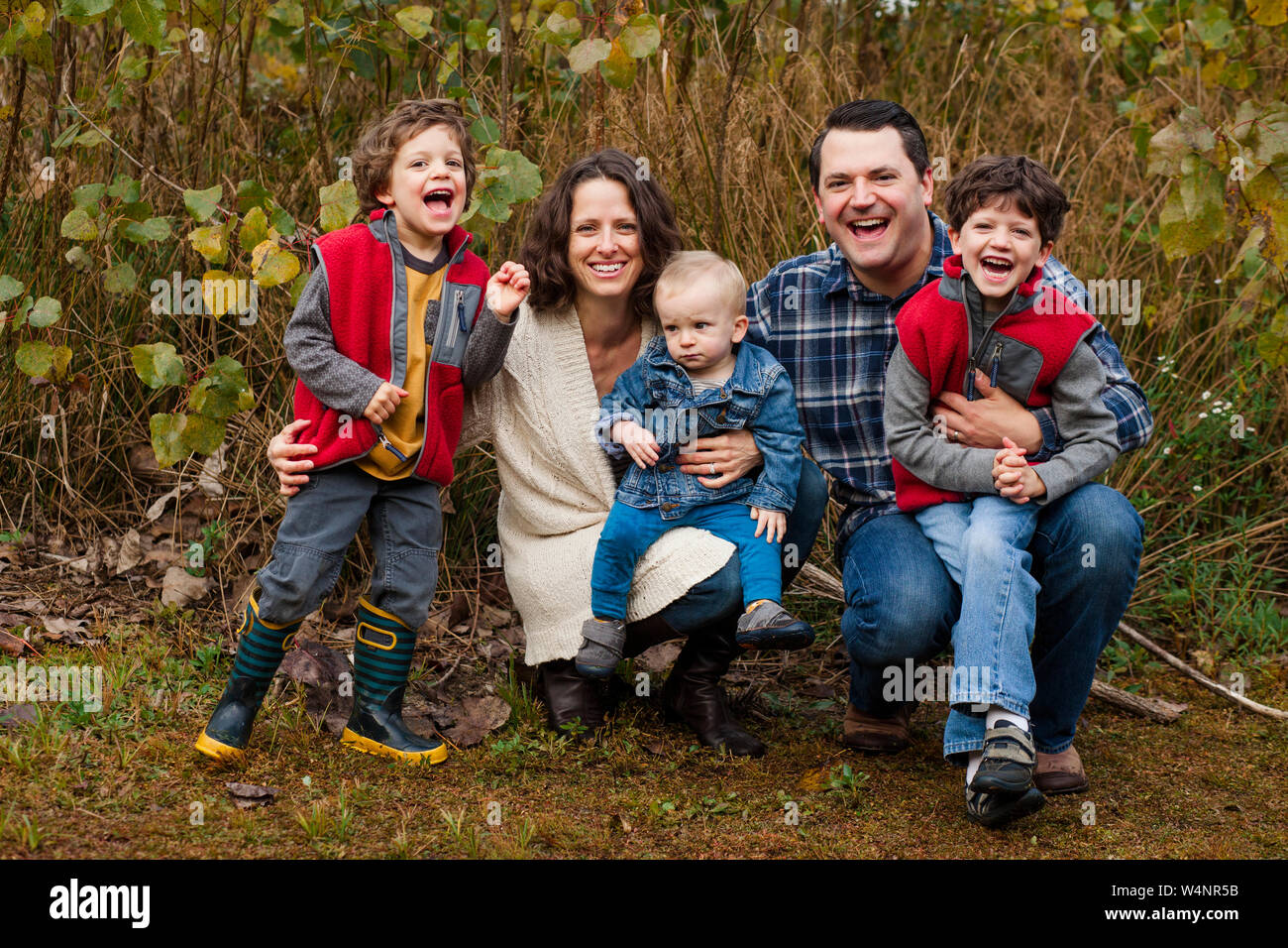 Un ridere famiglia felice sedersi vicino tether in una prateria erbosa Foto Stock