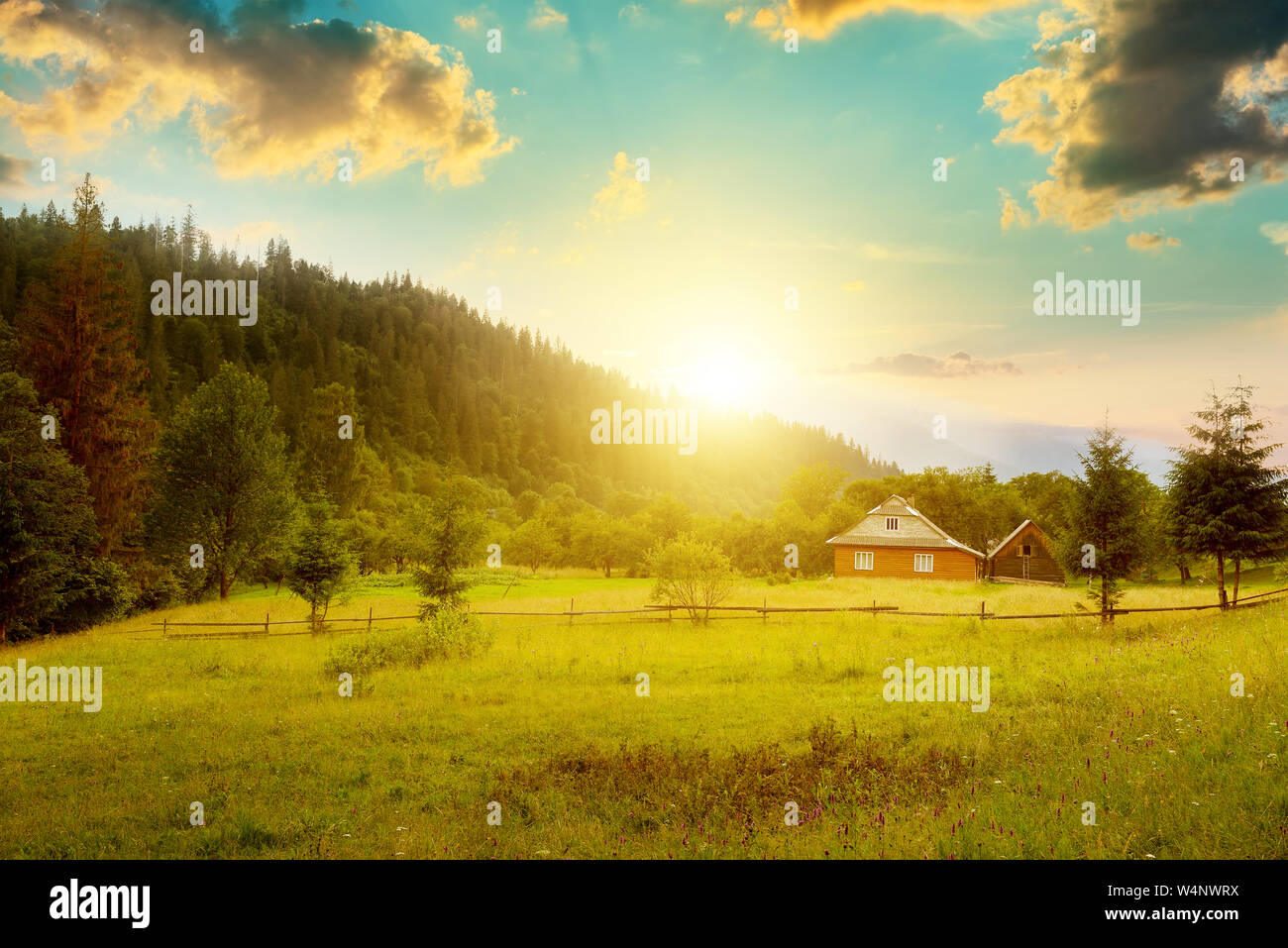Il pittoresco paesaggio di montagne. Piccola casa sul pendio dei Carpazi al tramonto. Foto Stock