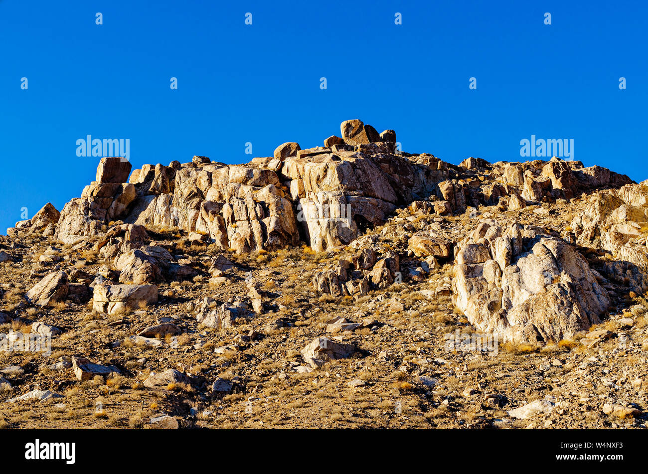 Ripido pendio roccioso sotto il luminoso cielo blu nel deserto di Mojave. Foto Stock