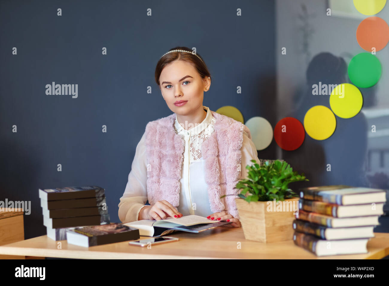 Collegio giovane donna seduta al tavolo nel campus cafe la lettura della nuova serie del libro - Happy smart ragazza adolescente godendo del tempo libero circondata da romanzi popolari Foto Stock