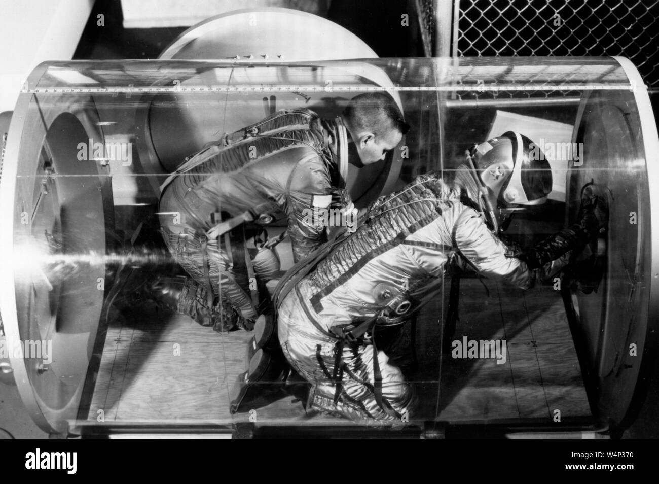 Gli scienziati della NASA il test degli astronauti capacità in movimento con il sistema di ritenuta di una tuta pressurizzata in plexiglass stazione spaziale airlock modello di test presso il Langley Research Center, Hampton, Virginia, 1966. Immagine cortesia Nazionale Aeronautica e Spaziale Administration (NASA). () Foto Stock