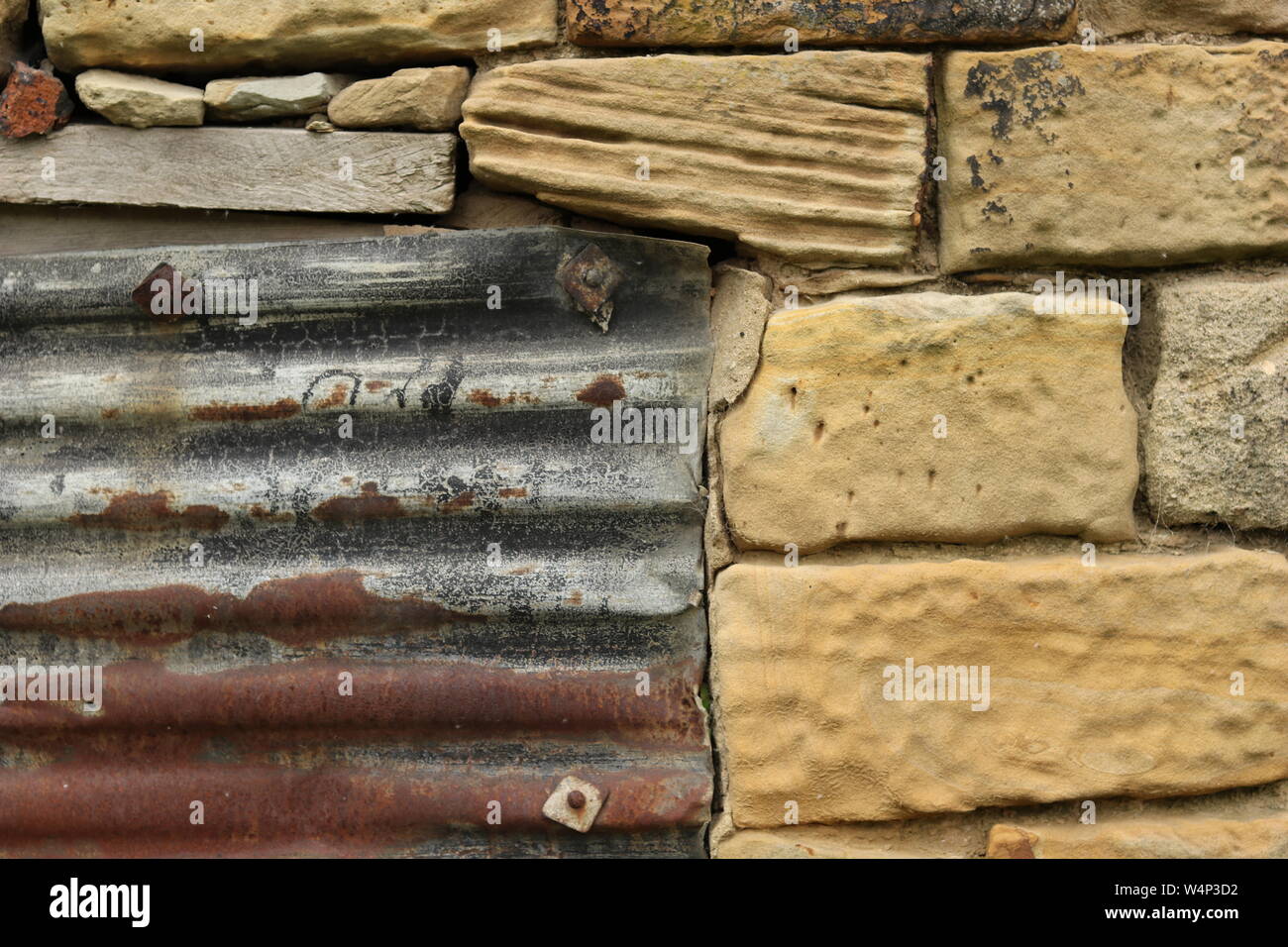 Un arrugginito lamiera grecata in acciaio su un fatiscente edificio di pietra Foto Stock