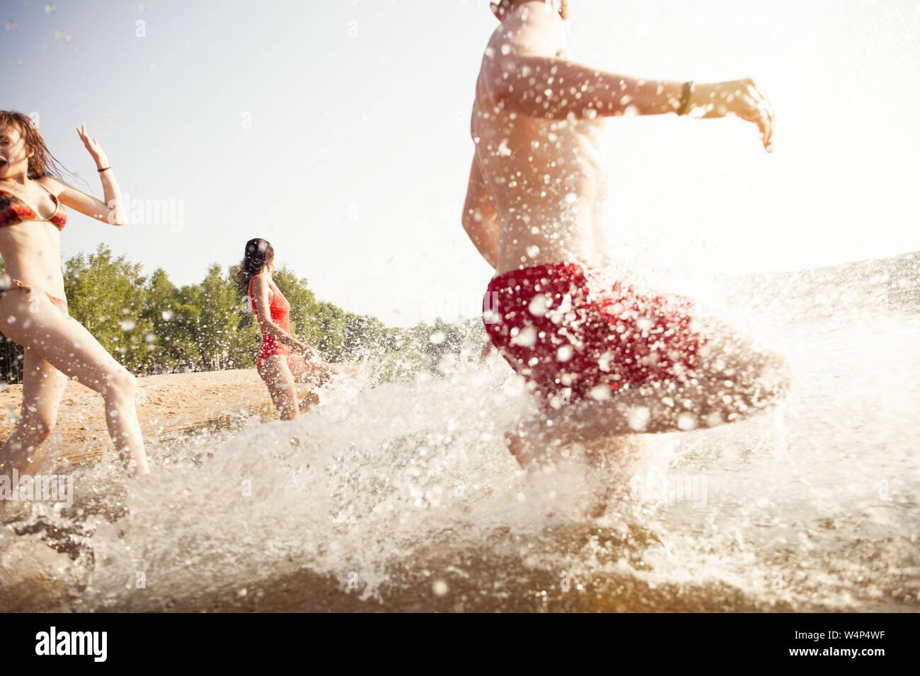 Il gruppo di amici di felice in esecuzione per acqua - le persone attive aventi il divertimento sulla spiaggia in vacanza Foto Stock