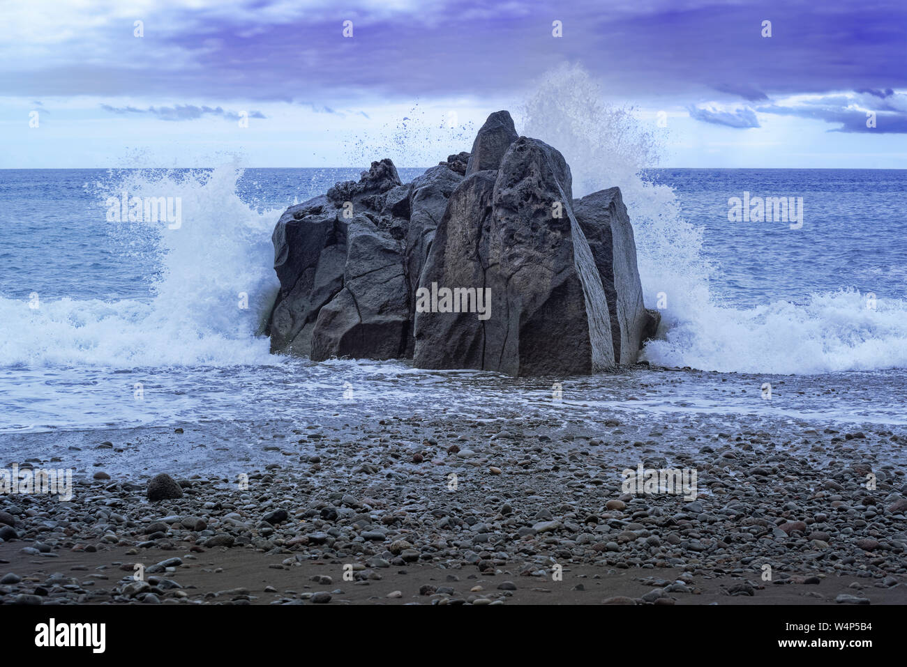 Spruzzi di onde al rock al tramonto. Praia Formosa beach a Funchal, Portogallo Foto Stock