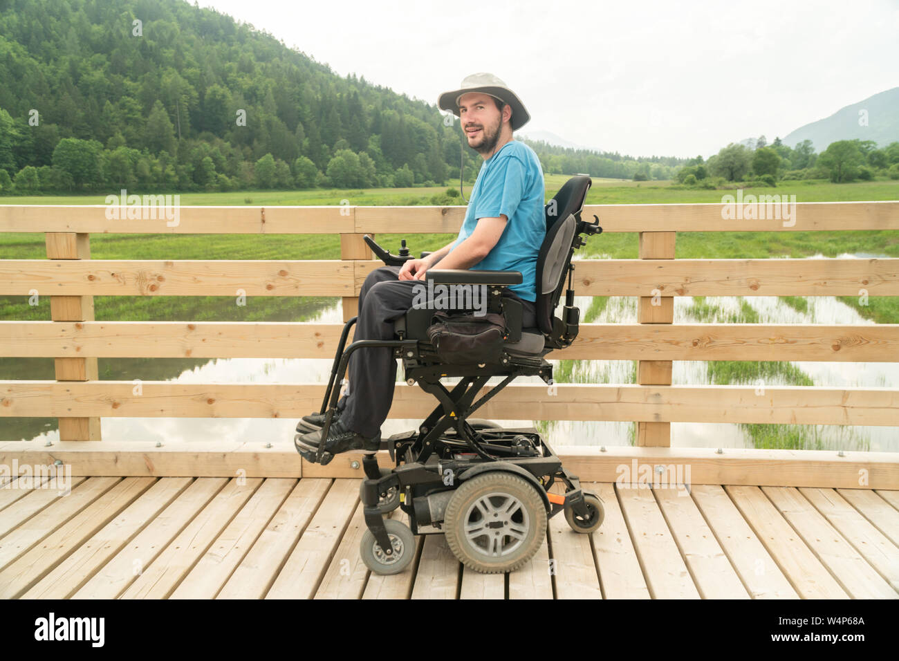 Disabilitato felice giovane in sedia elettrica su un lungomare godendo della sua libertà e sorridente Foto Stock