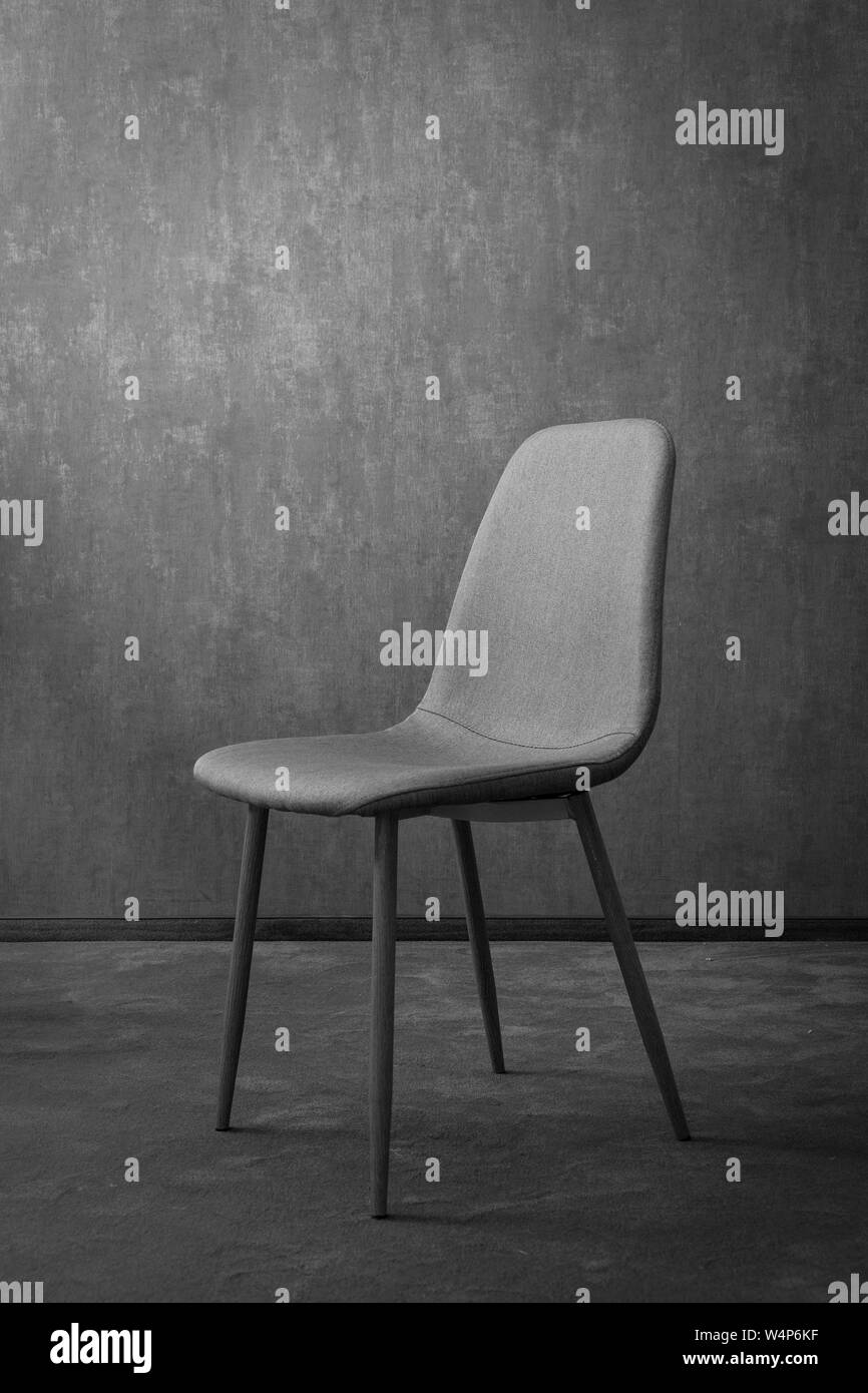 Grigio tessile moderno sedia con struttura in legno su uno sfondo di una parete. Buon concetto di hotel. Foto Stock