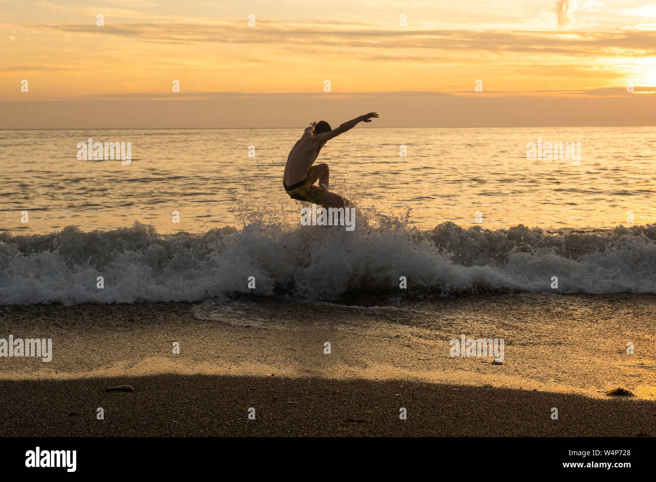 Aberystwyth, Wales, Regno Unito. Il 24 luglio 2019. Giovani uomini di scremare-imbarco su le onde che si rompono sulla spiaggia in Aberystwyth al tramonto su un altro ancora bruciante giorno come una nuvola di aria calda continua ad andare alla deriva dal continente. Le temperature sono attesi per raggiungere l'alta 30's Celsius in parti se il sud est del Regno Unito giovedì 25 luglio. Credito foto Keith Morris / Alamy Live News Foto Stock