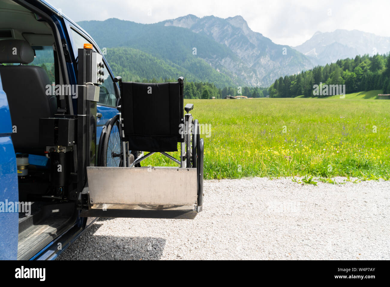 Il nero di sollevamento elettrico veicolo specializzato per le persone con disabilità. Sedia a rotelle vuota su una rampa con la natura e le montagne nella parte posteriore Foto Stock