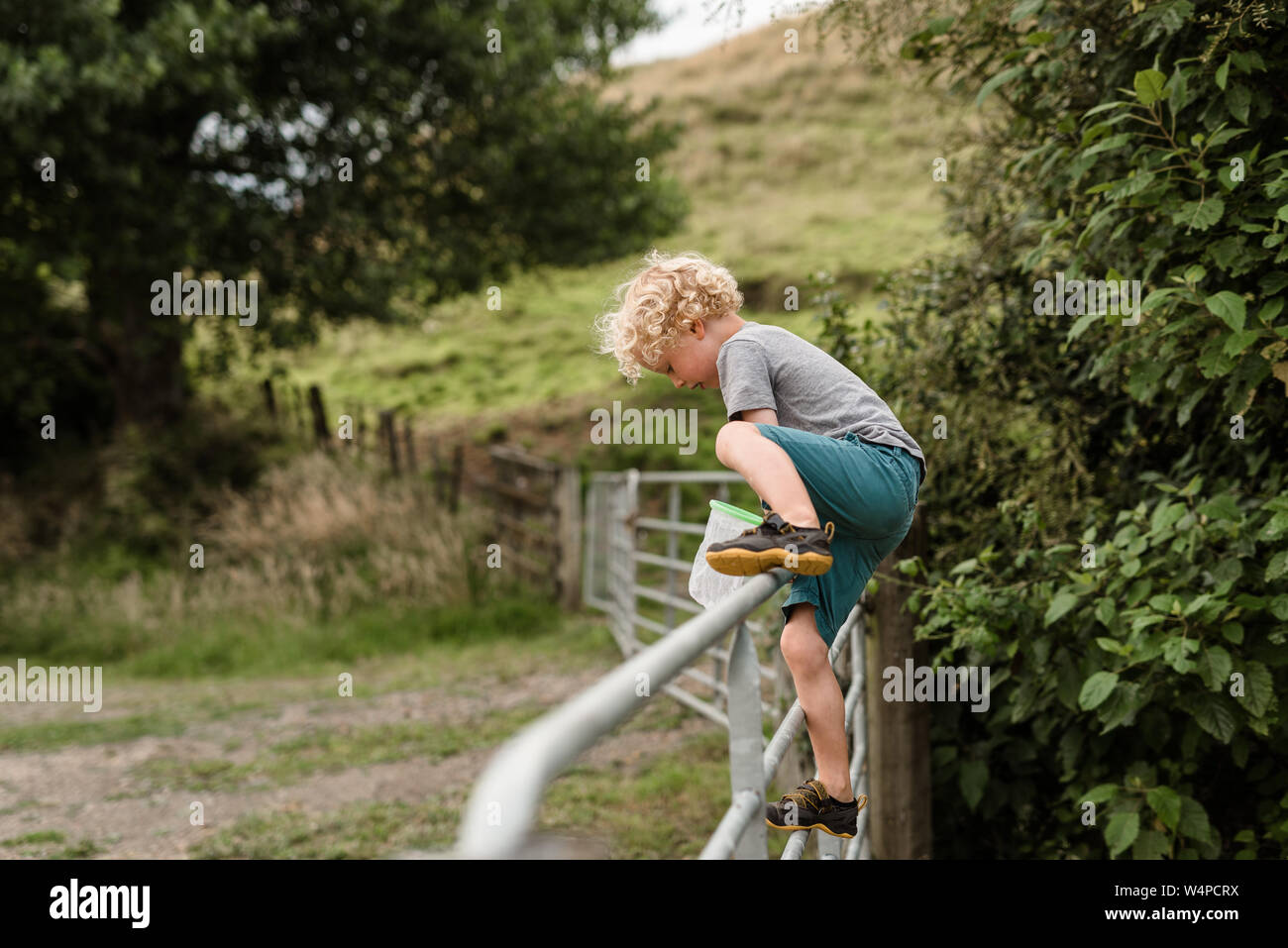 Attivo in modo indipendente il bambino che si arrampica sul recinto Foto Stock