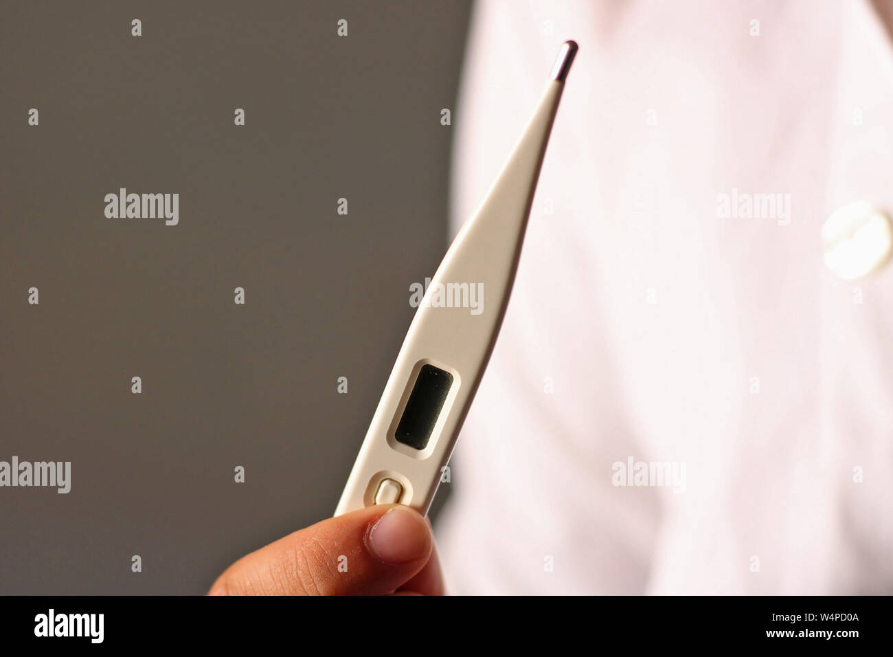 Medico vestito di bianco tenendo il termometro. Foto Stock