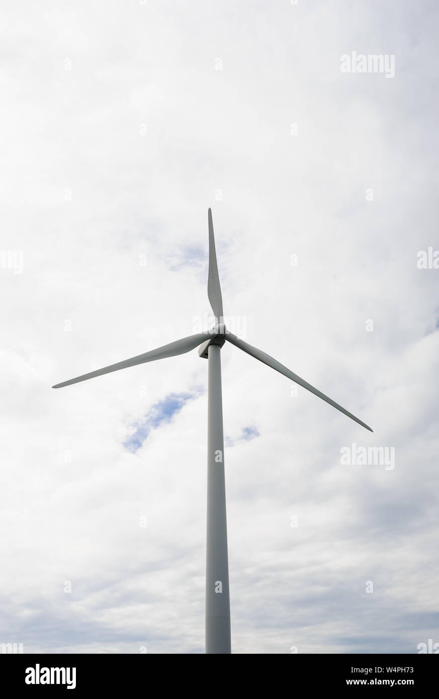 Singola turbina eolica contro il cielo nuvoloso. Foto Stock