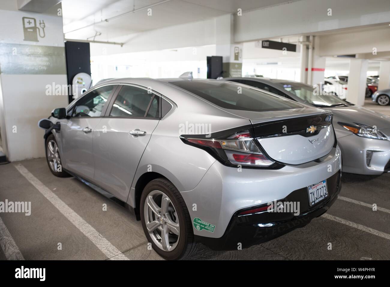 Chevrolet Volt veicolo elettrico collegato alla presa di corrente e la carica a un veicolo elettrico stazione di carica a San Ramon, in California, con accesso California Okay aria pulita veicoli sticker visibile, Settembre 26, 2018. () Foto Stock