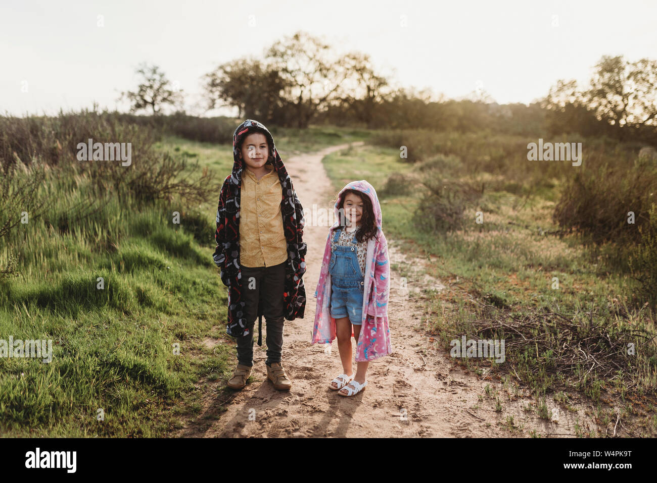 Studenti in età ragazzo e ragazza giovane che indossa vesti nel campo retroilluminato Foto Stock