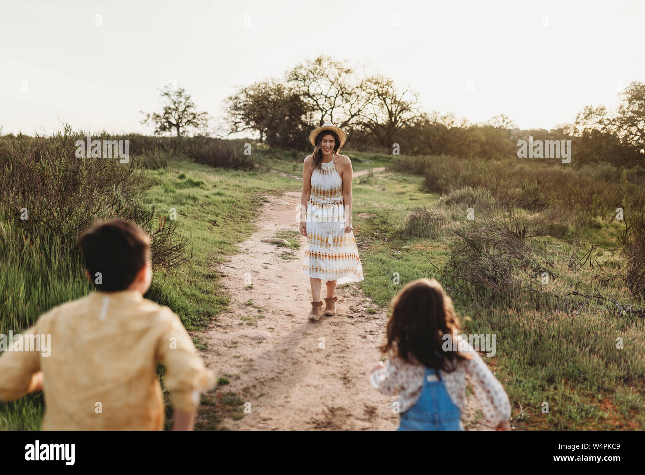 Giovane madre in piedi in attesa di campo per bambini di correre al suo Foto Stock