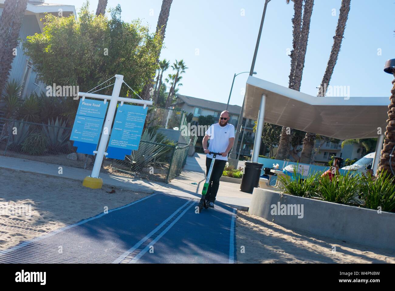 Un uomo adulto si prepara a cavalcare un scooter elettrico dalla condivisione della società di economia di calce sulla spiaggia di Marina nella Marina Del Rey quartiere di Los Angeles, California, 20 ottobre 2018. () Foto Stock