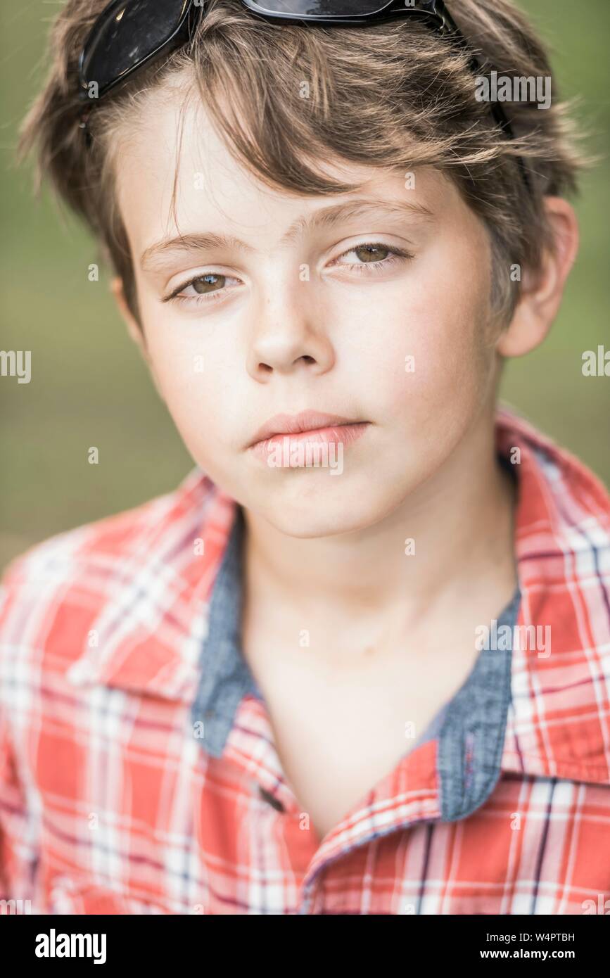 Il ragazzo, 10 anni, con plaid camicia guarda raffreddare nella fotocamera, Ritratto, Germania Foto Stock