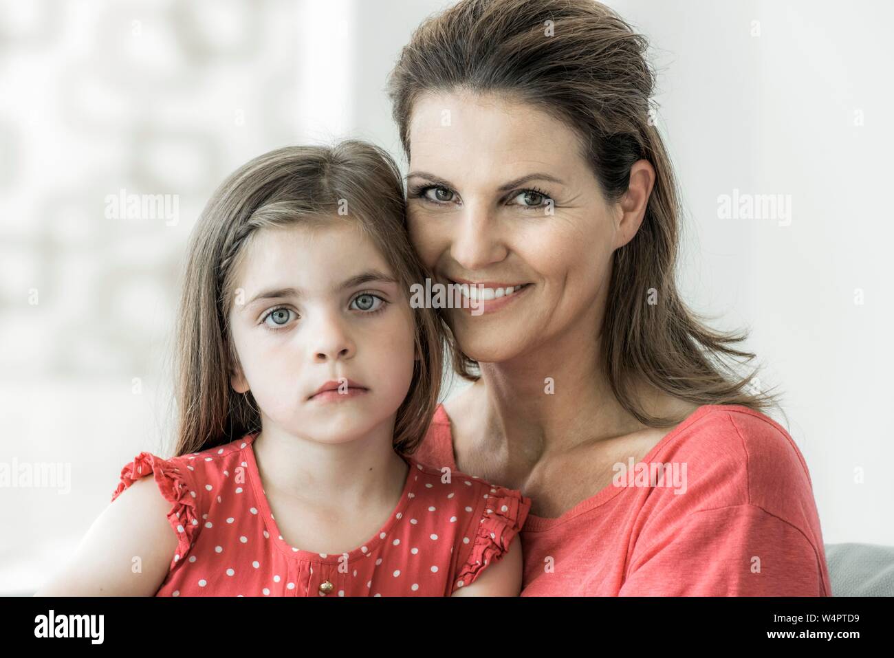 Madre e figlia insieme seduti sul divano e guardare la fotocamera, sorriso, Germania Foto Stock