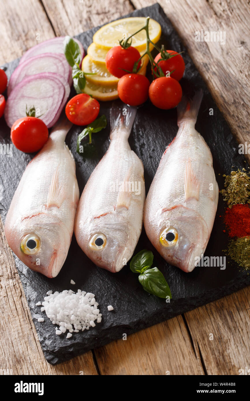 Orata bram di mare Pesce con ingredienti di close-up su una scheda di ardesia sul piano verticale. Foto Stock