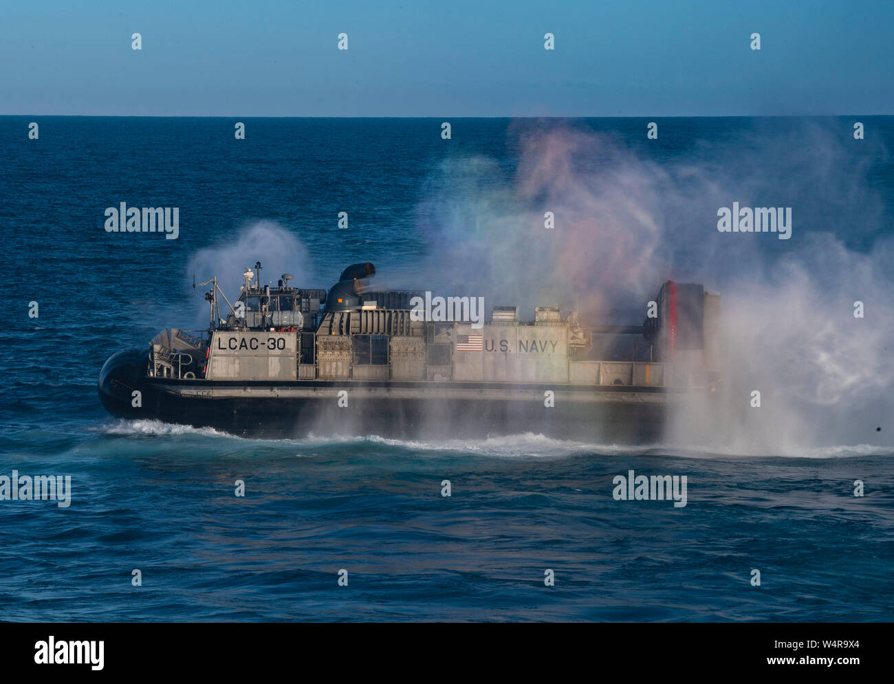 190724-N-BK435-0039 CORAL SEA (Luglio 24, 2019) - un arcobaleno appare come Landing Craft, cuscino d'aria (LCAC) 30, assegnato alla spiaggia navale unità (NBU) 7, si diparte la ben coperta dell'assalto anfibio nave USS Wasp (LHD 1). Wasp, ammiraglia di Wasp Expeditionary Strike gruppo, con avviato 31 Marine Expeditionary Unit, partecipa attualmente a Talisman Sabre 2019 al largo delle coste del nord Australia. Un accordo bilaterale, evento biennale, Talisman Sabre è progettato per migliorare NEGLI STATI UNITI Australia e combattere la formazione, la disponibilità e l' interoperabilità attraverso l' realistico, formazione pertinenti necessarie per mantenere ri Foto Stock