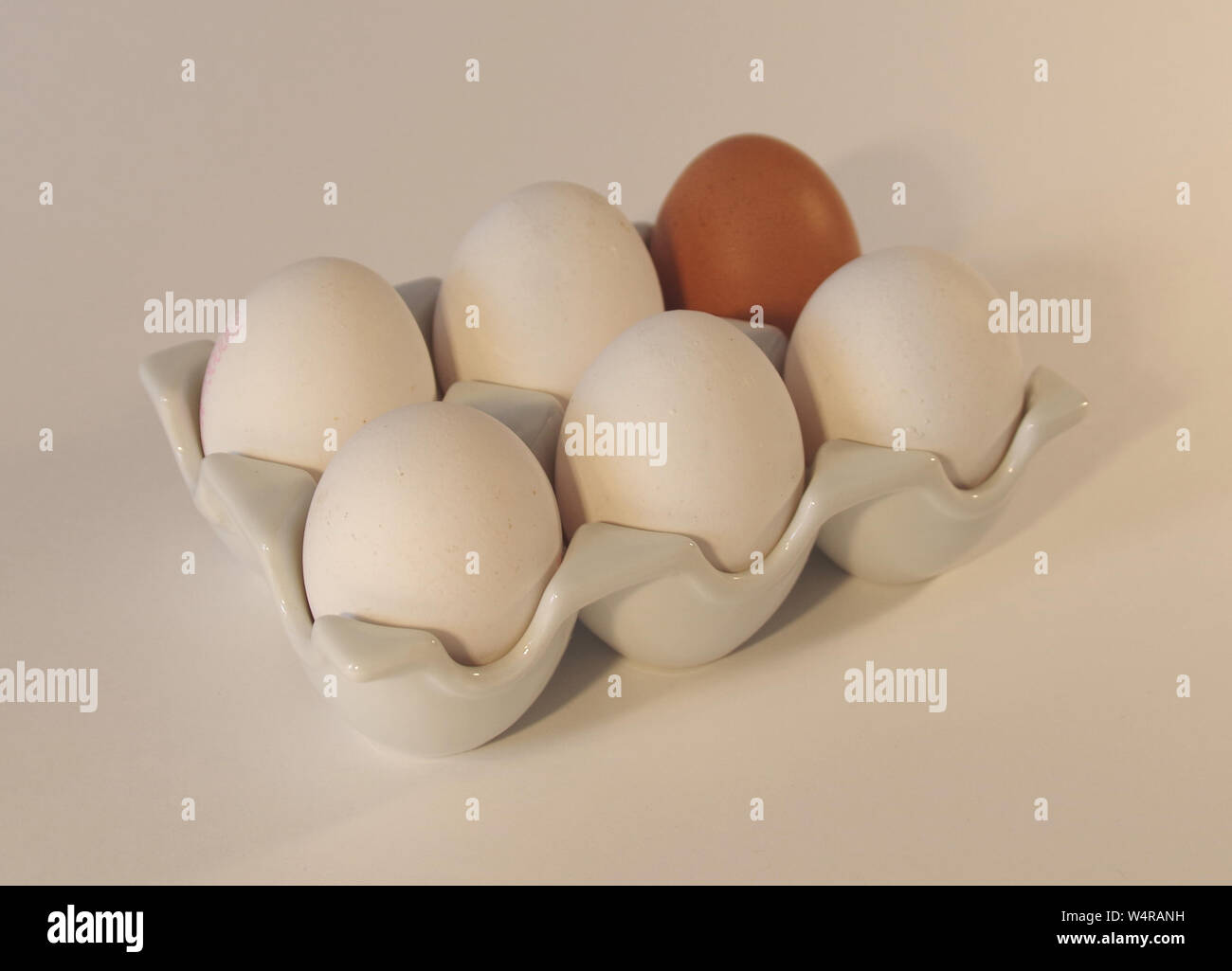 Sei uova in ceramica; uno browm e cinque uova di colore bianco Foto Stock