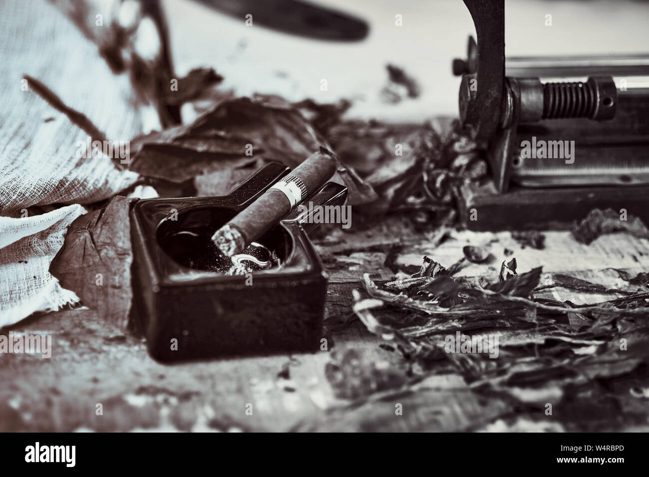 Close up di un sigaro cubano e un nero Posacenere in ceramica sul tavolo di legno whit essiccato ed indurito foglie di tabacco. immagine bw Foto Stock