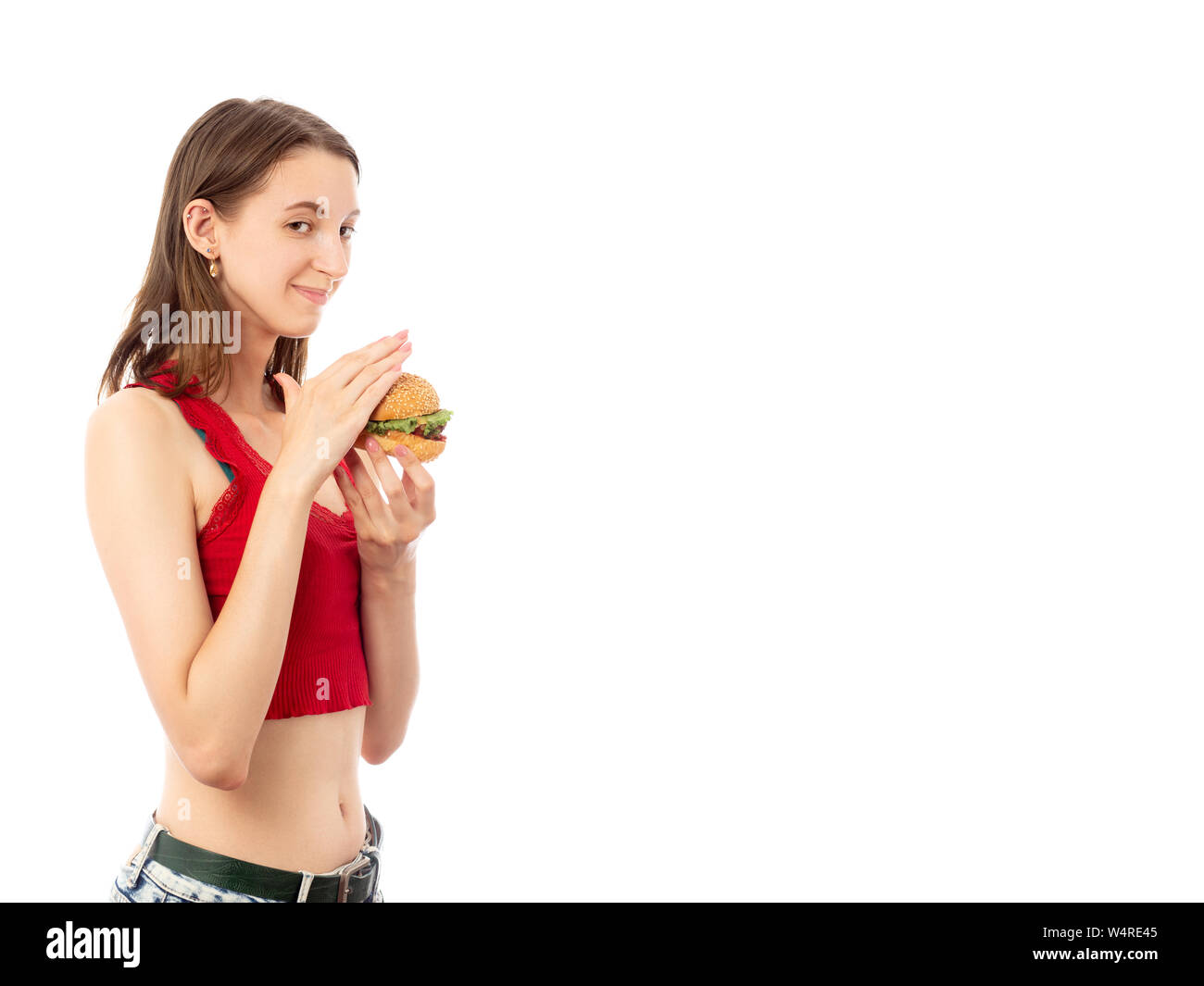 Felice timido giovane donna con hamburger su sfondo bianco con copia spazio isolato guardando sorridente della fotocamera Foto Stock