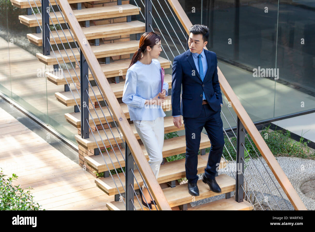Manager e segretario a piedi giù per le scale, Pechino, Cina Foto Stock
