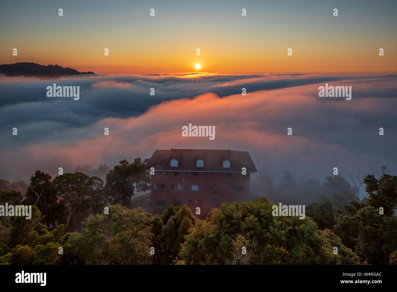 Casa nella nebbia sulla cima di una collina con il tramonto dietro, Miaoli County, Taiwan Foto Stock