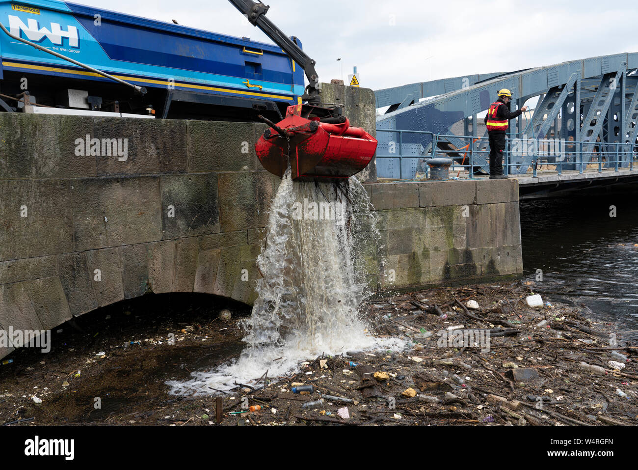 Pulire i detriti raccolti a ponte sulle acque del fiume di Leith a Leith Dopo forti piogge, Scotland, Regno Unito Foto Stock
