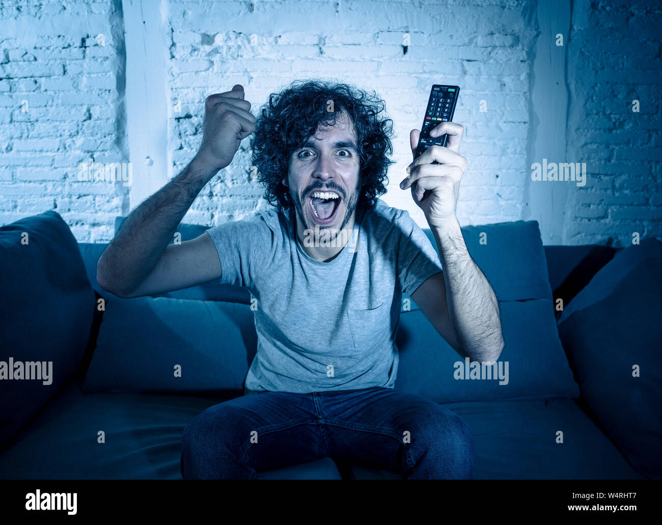Stile di vita ritratto di tv show man ventola guardando eccitato serie preferita filmato o di calcio partita di calcio in TV online a tarda notte. In streaming le persone c Foto Stock